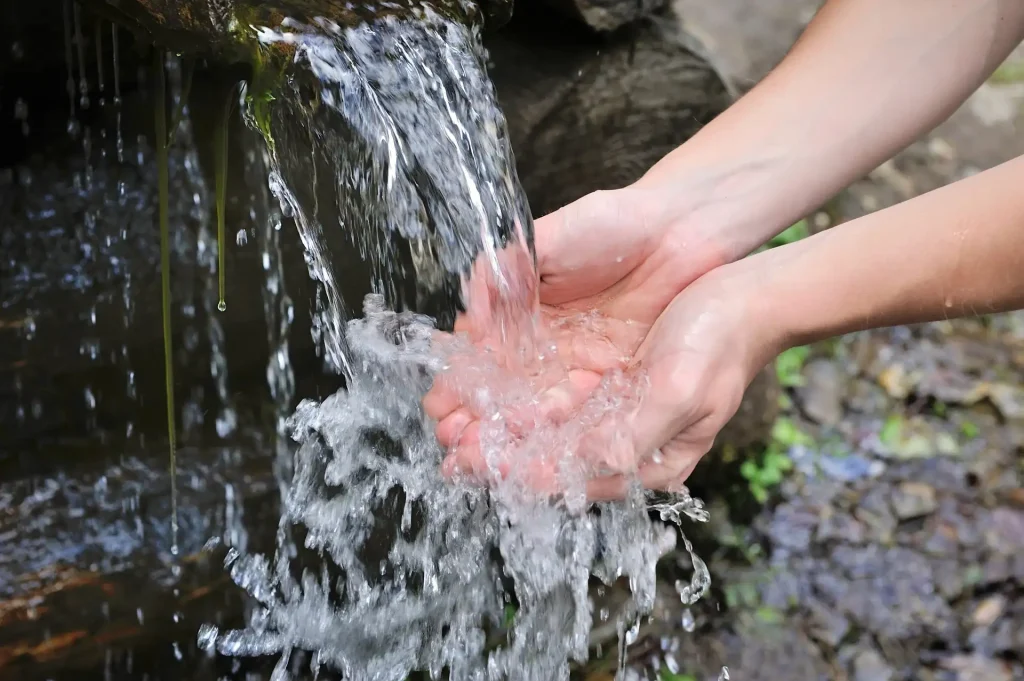 Zwei Hände fangen fließendes Wasser draussen in der Natur ein als Beispielbild für Hausmeisterservice in Wiesbaden